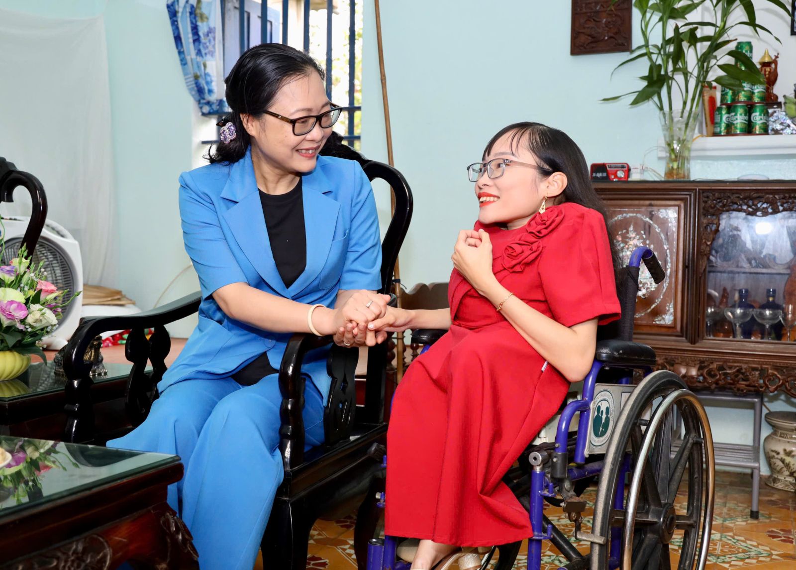 A person holding hands with another person in a wheelchair Description automatically generated