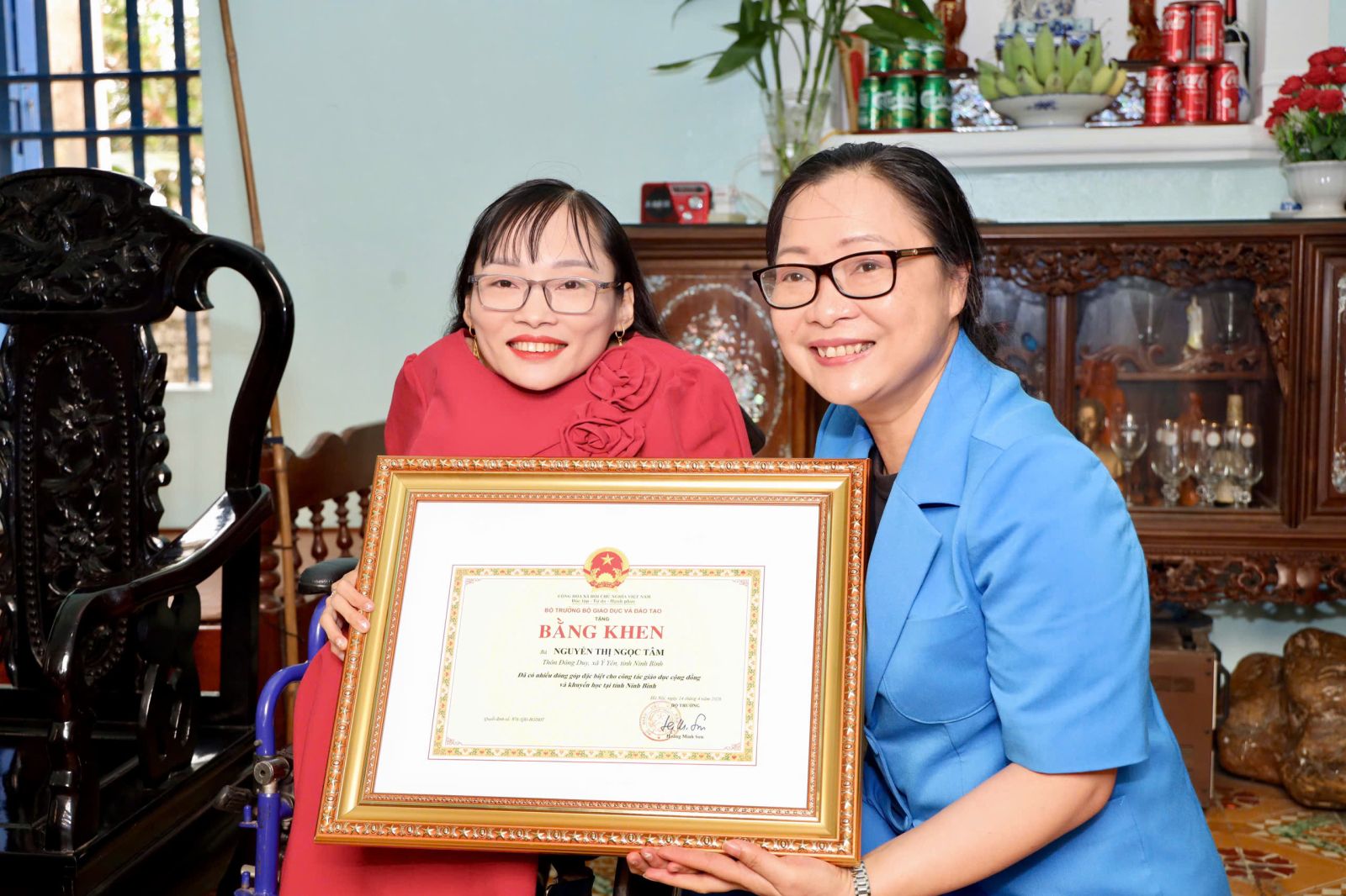 Two women holding a framed certificate Description automatically generated